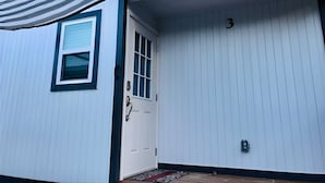 Una casa con fachada blanca, una puerta azul y el número 3 en la pared.