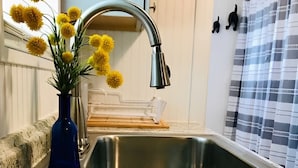 Una cocina con encimera de granito, pileta de acero inoxidable y un florero azul con flores amarillas.