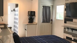Un dormitorio con cama, televisor, escritorio con lámpara y un cartel que dice LABRADOR LANE.
