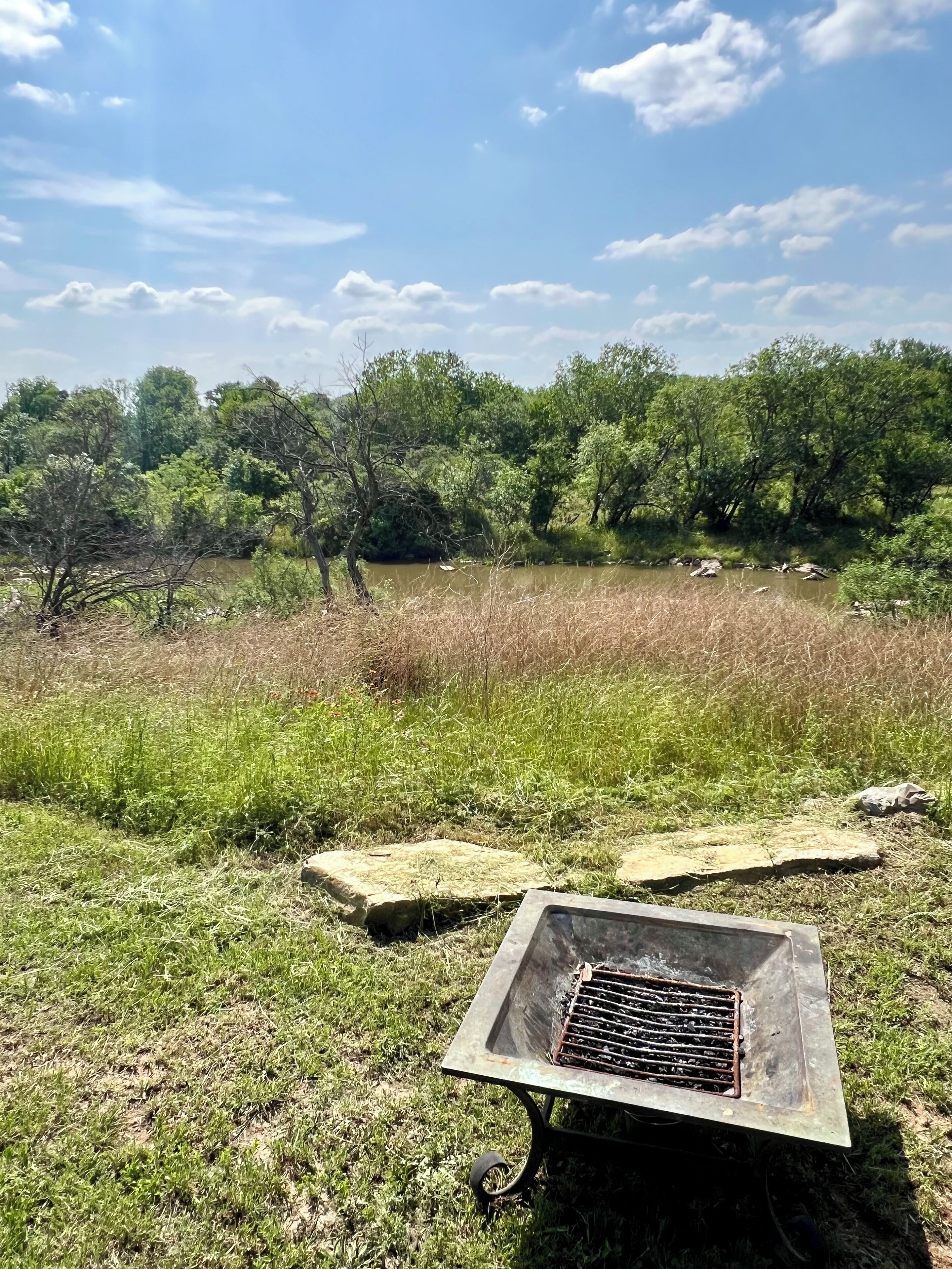 A grassy area with a metal grill and stones.
