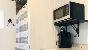 Een kleine keuken met een magnetron, koffiezetapparaat en een koelkast.