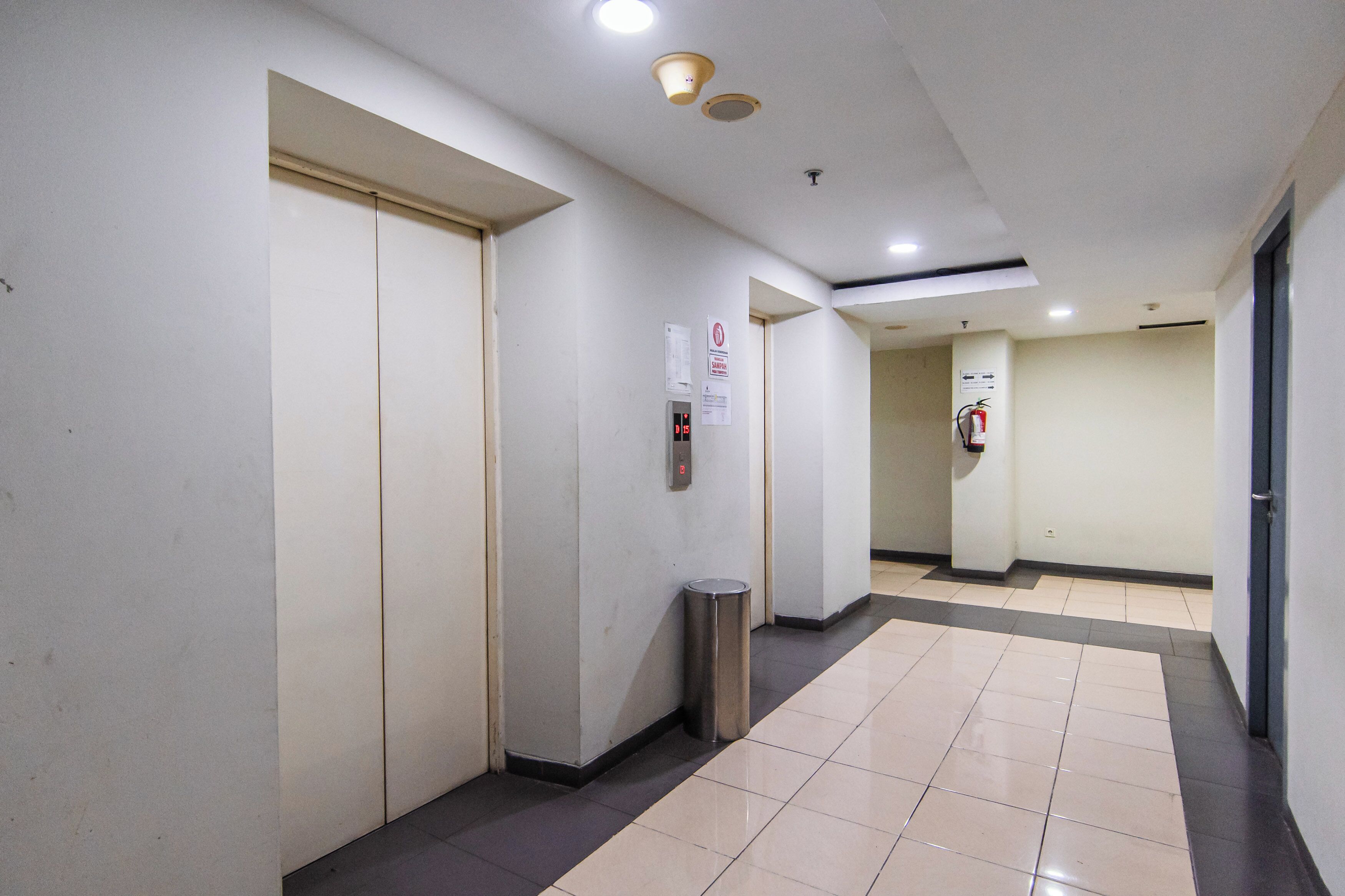A clean, well-lit hallway with a trash bin, a fire extinguisher, and a door on the left.
