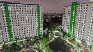 A high-rise residential building with multiple floors, a central courtyard with a water feature, and surrounding greenery.