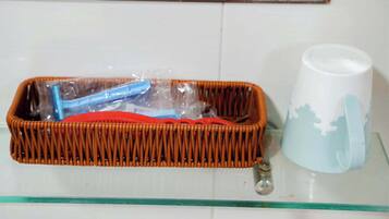 Una cesta de mimbre con interior rojo y un objeto azul en su interior, sobre un estante de vidrio junto a una taza blanca con un diseño azul.