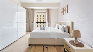 Ein modernes Hotelzimmer mit einem großen Bett, einem Nachttisch mit Lampe, Blick auf die Stadt durch raumhohe Fenster und einer Wand mit geometrischem Muster.