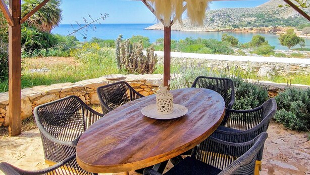 Un espace extérieur abrité, aménagé pour prendre les repas, avec une table et des chaises, offrant une vue sur un paysage pittoresque.