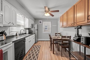 A kitchen with white cabinets, a wooden dining table, and a ceiling fan. - Tranquil 2BR Apt Mpls - 8075 Apt 2 (Minneapolis)