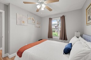 A bedroom with a bed, ceiling fan, window with curtains, and artwork on the wall. - Tranquil 2BR Apt Mpls - 8075 Apt 2 (Minneapolis)