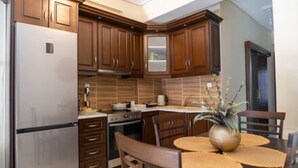 Una cucina con mobili in legno, un frigorifero, un forno e un tavolo da pranzo con sedie.