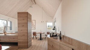 A modern kitchen with wooden cabinetry, a dining area with two chairs, and a large window providing natural light. - Winzerhäuser Skringer (Leutschach)