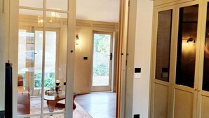 A hallway with a wooden floor, a glass door leading to a balcony, and a hanging lantern. - "The Chadwick" Unique, High-end Boutique. (Soldiers Hill)