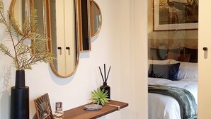 A bedroom with a bed, a nightstand, and a mirror. - "The Chadwick" Unique, High-end Boutique. (Soldiers Hill)