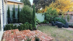 A backyard with a brick patio, outdoor furniture, and a green fence. - "The Chadwick" Unique, High-end Boutique. (Soldiers Hill)