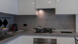 Uma cozinha moderna com armários brancos, fogão a gás e forno embutido.