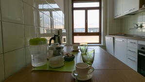 A modern kitchen with white cabinets, a wooden countertop, and a window overlooking a cityscape. - Ponte Vecchio Family Apartment (Lecco)
