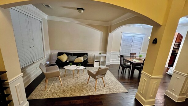 A living room with a black sofa, two white coffee tables, and a patterned rug.