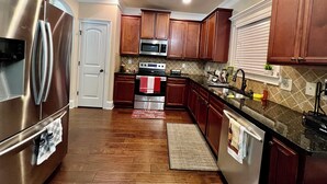 A kitchen with stainless steel appliances, wooden cabinets, a tiled backsplash, and a built-in oven.