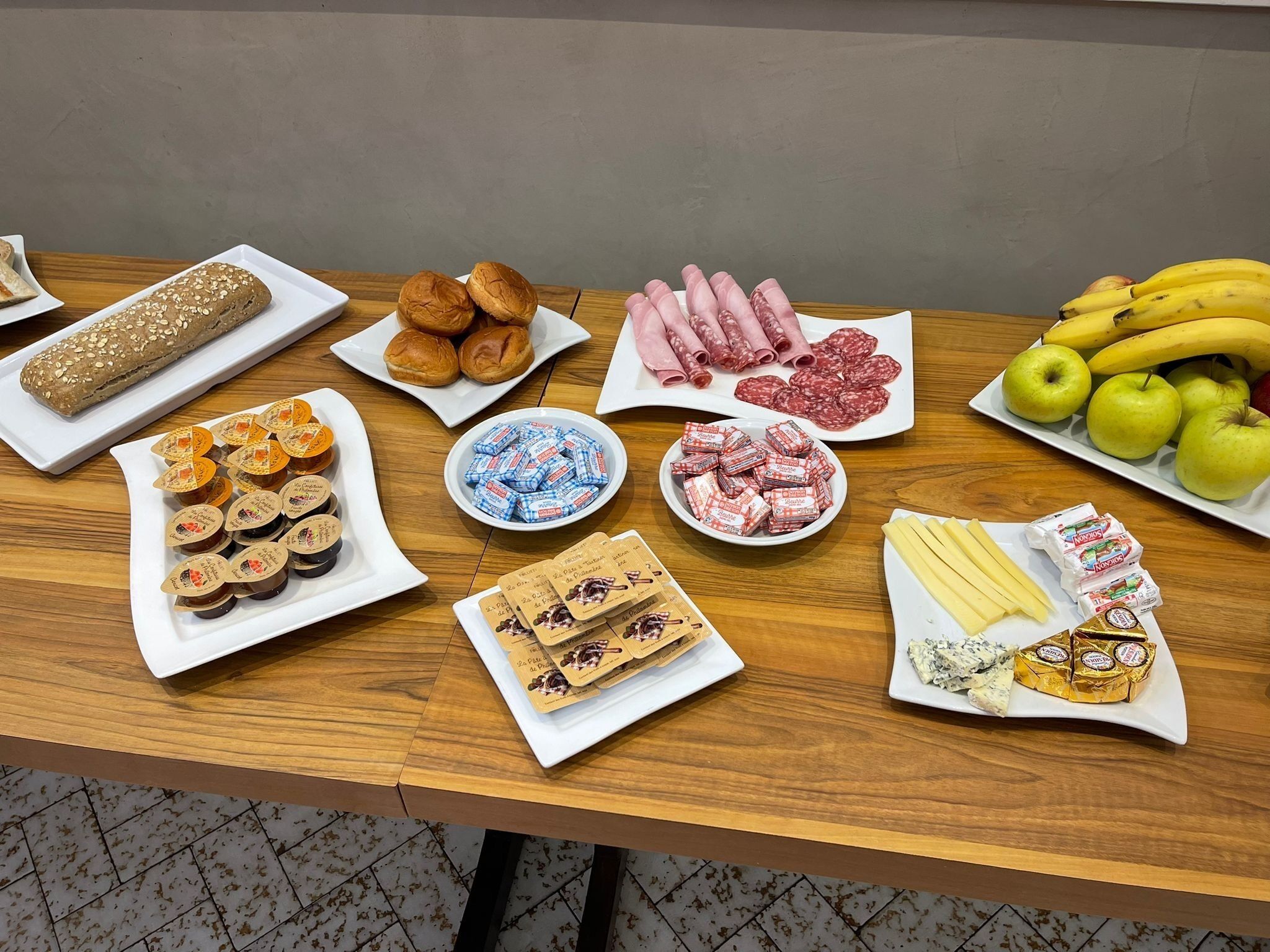 A table with various food items including bread, pastries, cured meats, cheeses, and fruits.