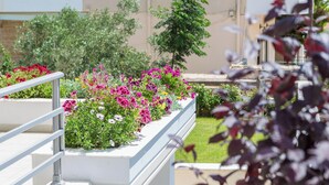 A balcony with a railing, surrounded by a variety of flowering plants and greenery. - Santa Barbara 2fl Home w. Garden and Intex Pool (Marathonas)