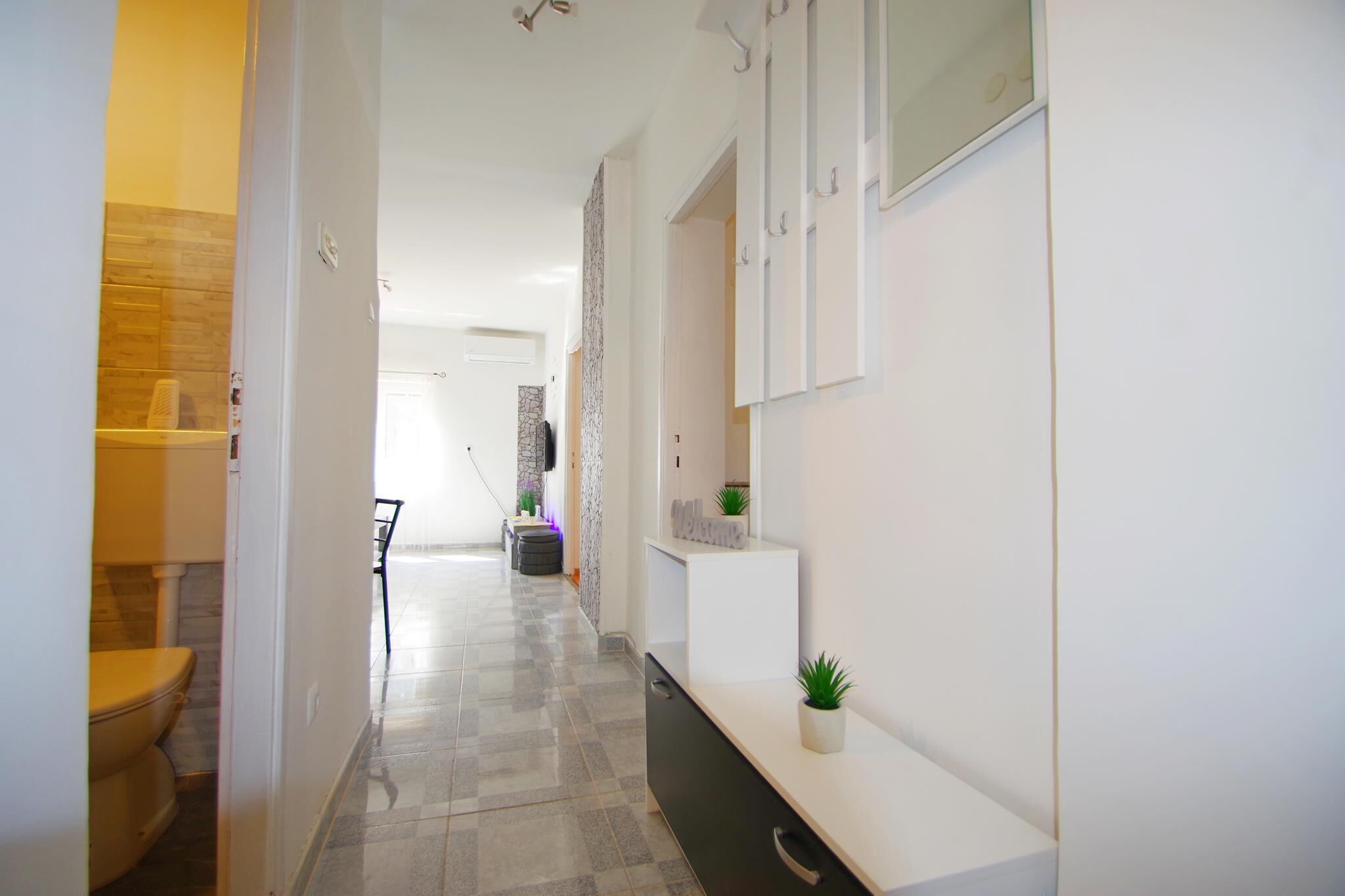 A hallway with a white reception desk, a small plant, and a tiled floor.