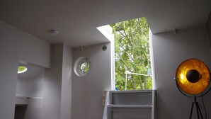 Ein Zimmer mit einer Dachfensterkuppel, einer weißen Sprosse, einem Feuerlöscher und einer Stehlampe.