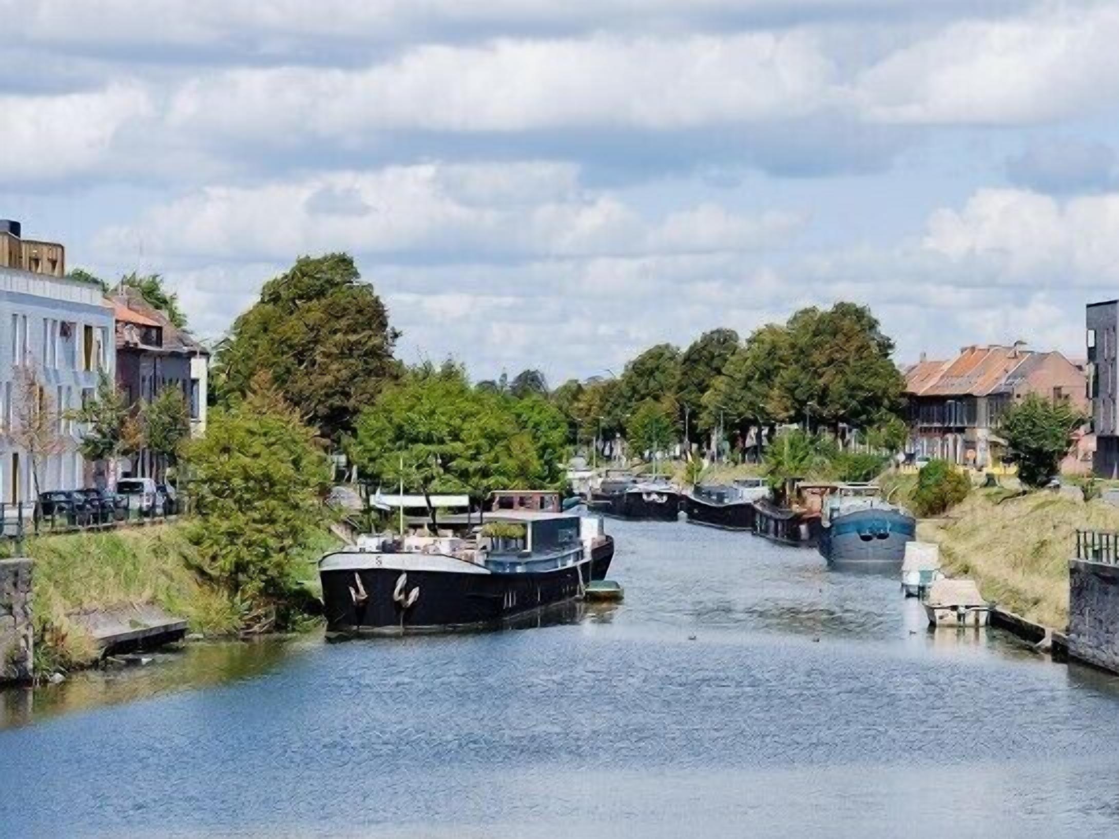 A canal with boats, surrounded by buildings and trees.