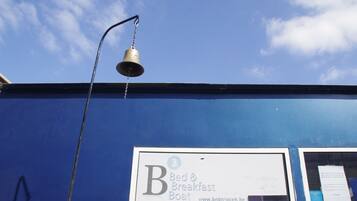 A blue building with a sign for 'Bed & Breakfast Boat' and a bell hanging from a pole.