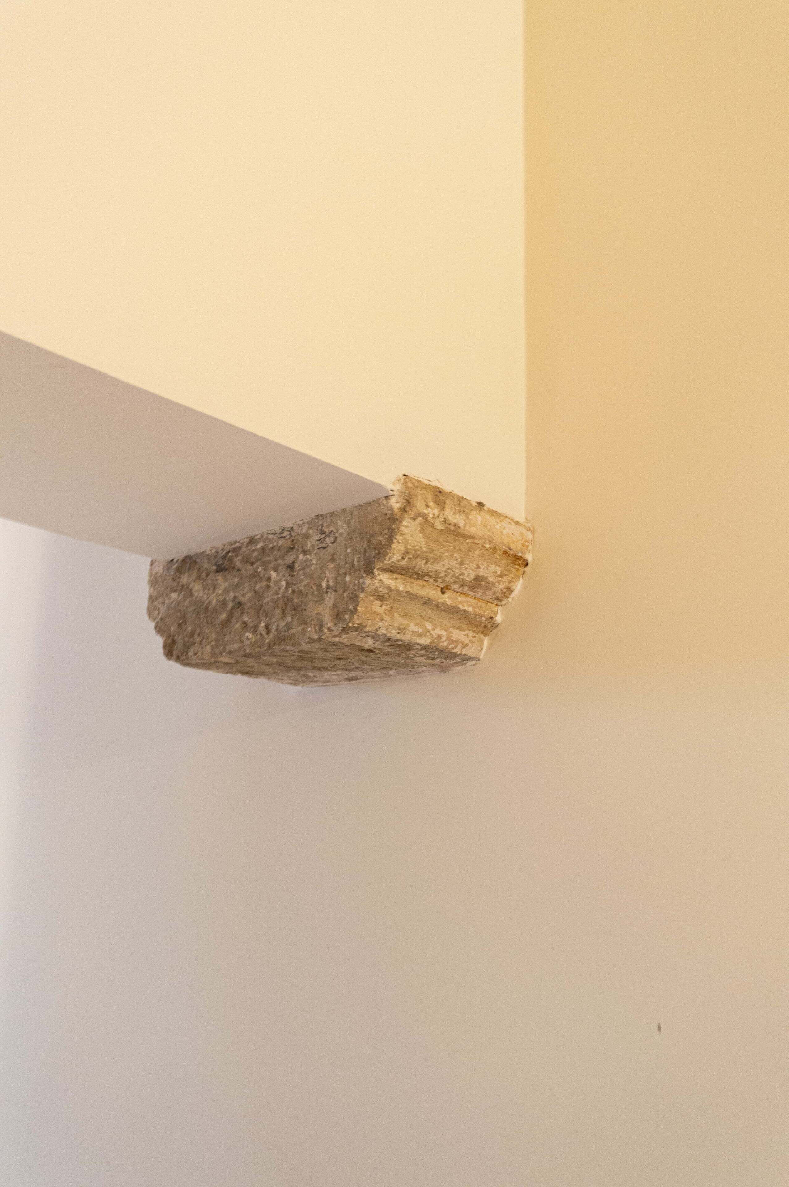 A corner of a room with a white wall and a stone or brick column.