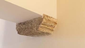 A corner of a room with a white wall and a stone or brick column.