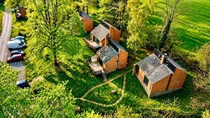 A cluster of brick buildings with a circular driveway, surrounded by lush greenery and parked vehicles. - Havane13 -Quietly located, fully furnished holiday home (Hastiere)