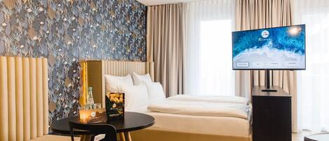 Una habitación de hotel moderna con una cama, un escritorio, un televisor y una pared con un diseño de hojas.
