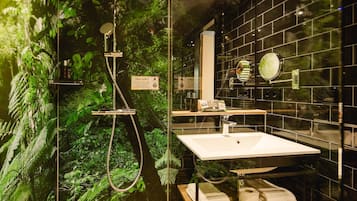 Casa de banho moderna com chuveiro em cabine de vidro, lavatório branco e espelho.