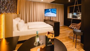 A modern hotel room with a bed, a TV, a dining area with a table, and a hanging chair. - Rioca Konstanz Posto 10 (Konstanz)