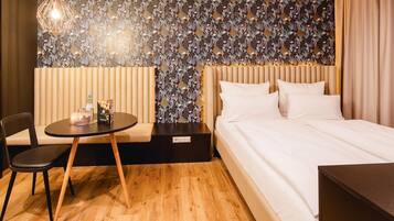 Ein Hotelzimmer mit einem Bett, einem runden Tisch mit Stuhl, einer Wand mit Dekoration und einer Pendelleuchte.