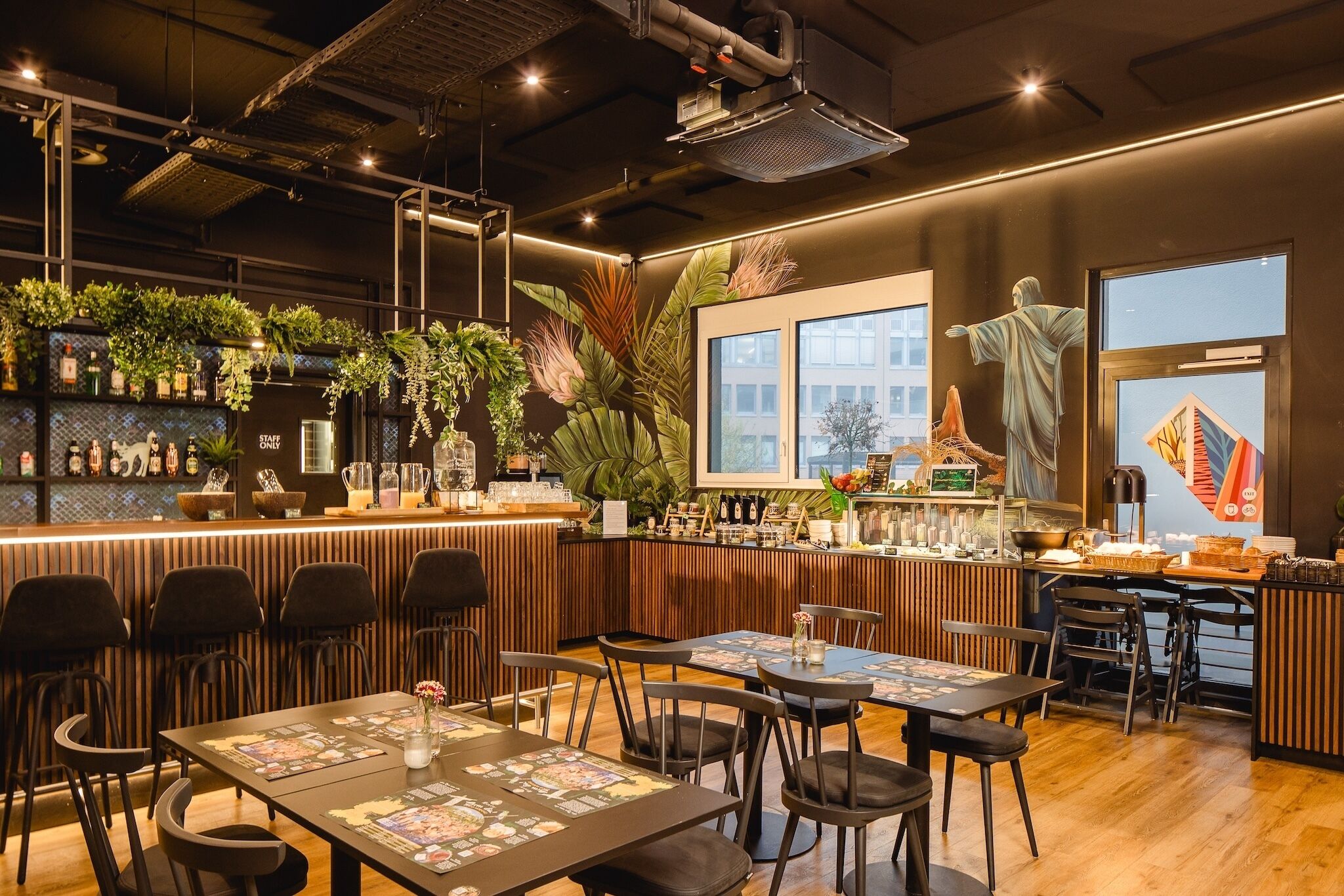 A restaurant interior with a bar area, seating, and decorative plants.