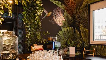 A bar area with a wooden counter, glassware, and a large plant.