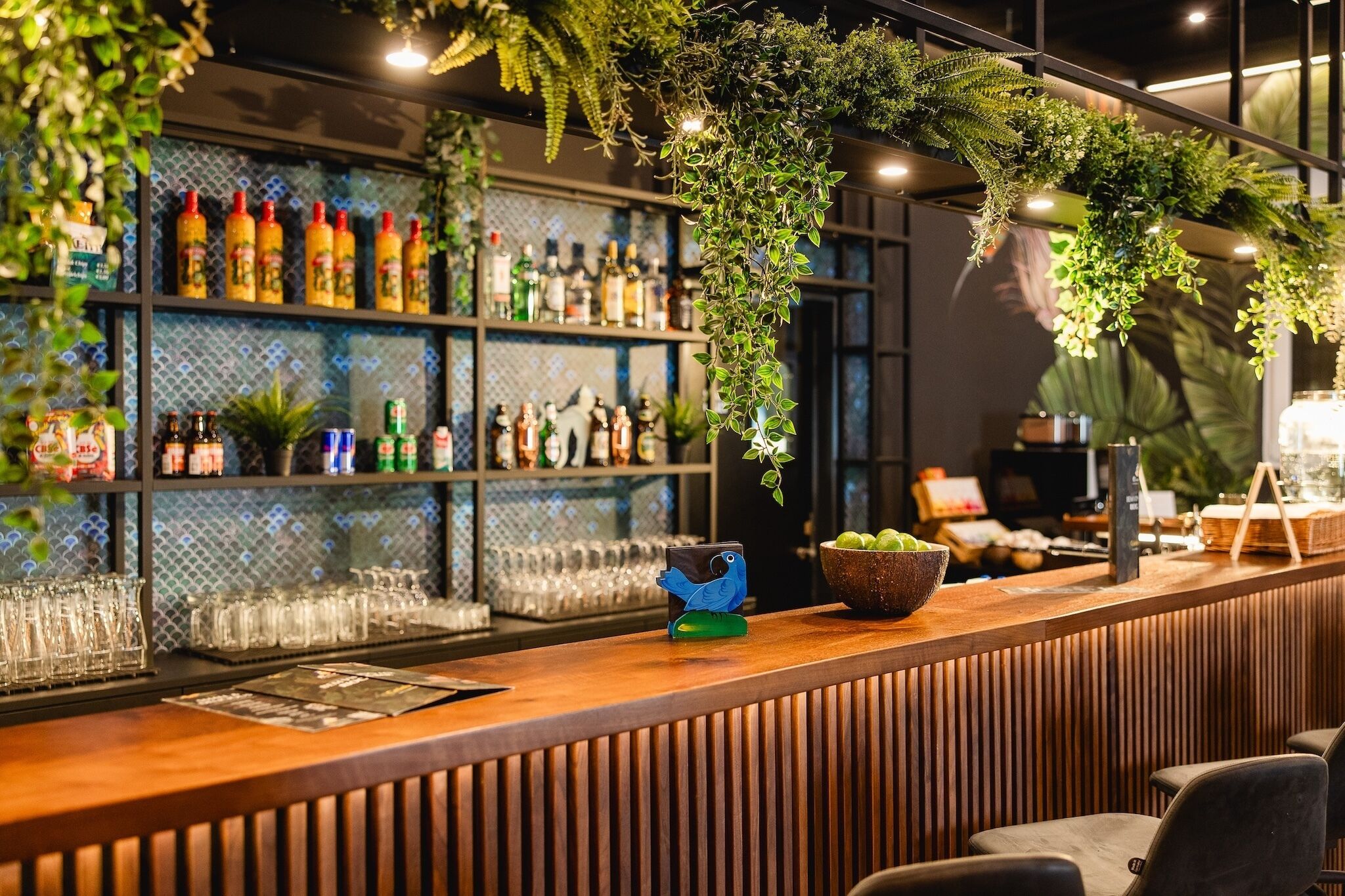 Un espace bar avec des étagères remplies de bouteilles et de verres, ainsi qu’un comptoir en bois.
