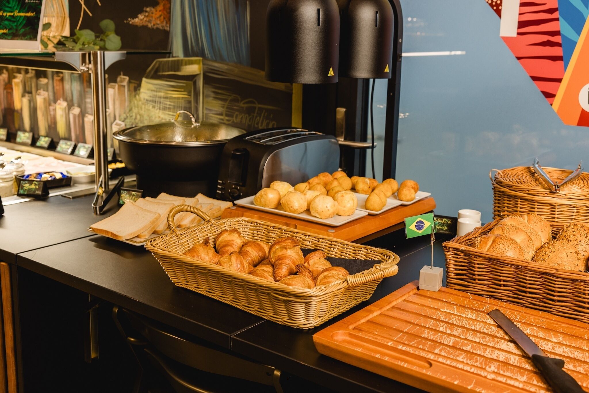 Un bufé con diversas opciones de comida, incluyendo pan, pastelería y una máquina de café.