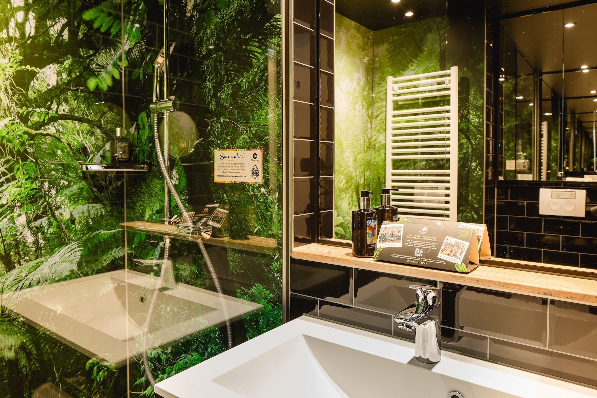 Een moderne badkamer met een wastafel met glazen ombouw, een douche met glazen deur en een spiegel die de ruimte weerspiegelt.