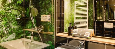 Un baño moderno con un lavabo con cristal, ducha con puerta de cristal y un espejo que refleja la habitación.