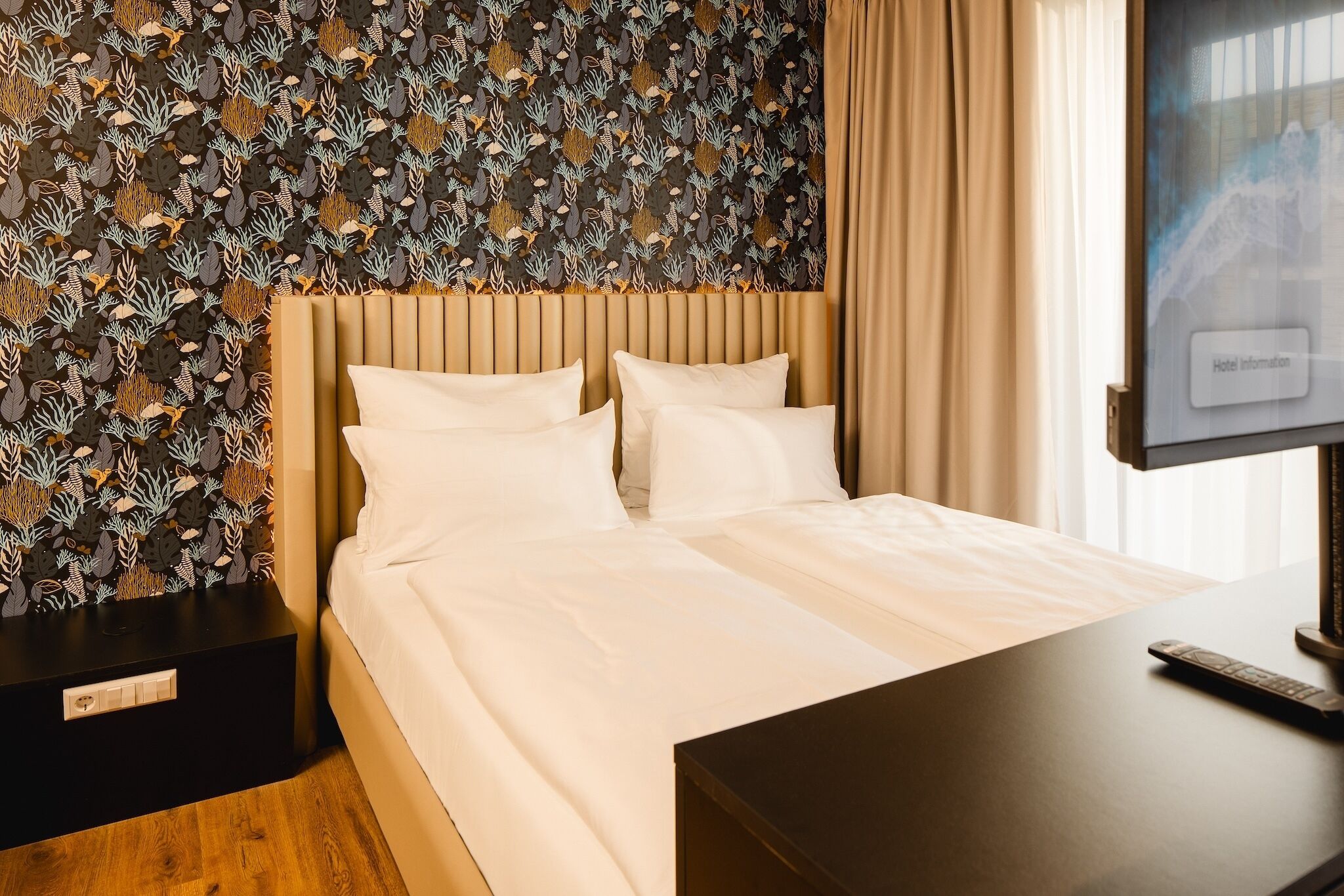 Una habitación de hotel con una cama, un televisor y una mesita de noche.