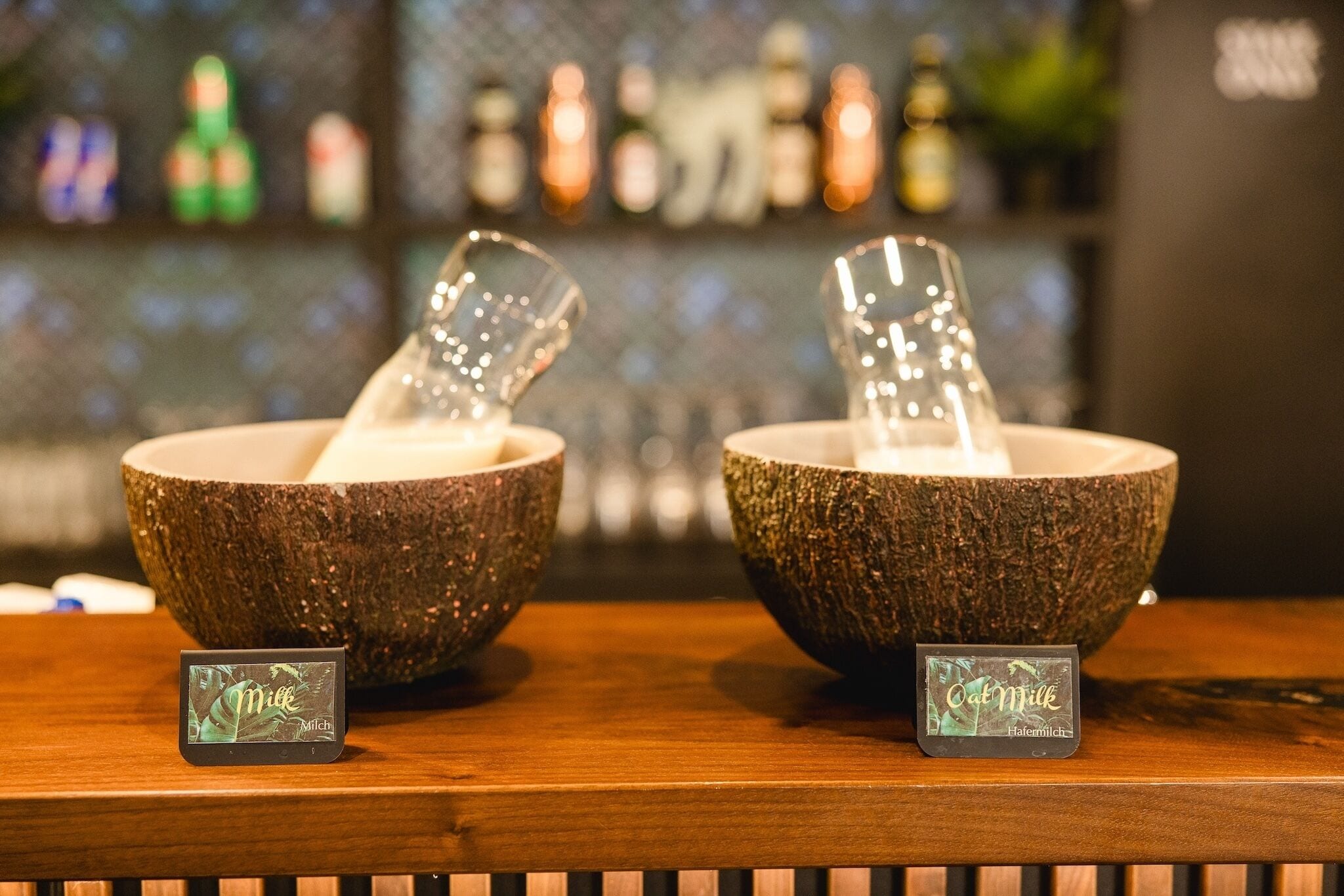 Two bowls with glasses on a wooden surface, each with a label.