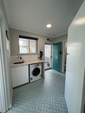 A laundry room with a washing machine, sink, and window.