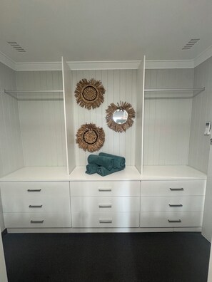 A white wardrobe with multiple drawers and a mirror.