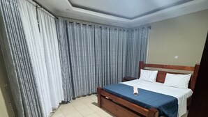 Una camera da letto con un letto, tende e pavimento piastrellato.