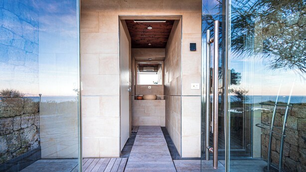 Une salle de bain moderne avec un plafond en bois, une douche en verre et une vue sur la mer.