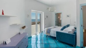 A bedroom with a bed, a dresser, a door leading to a balcony, and a ceiling light.