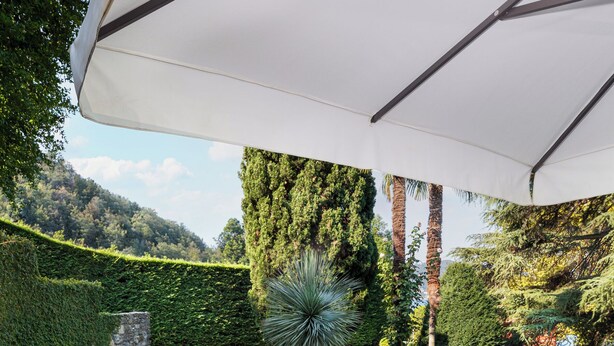 Une terrasse extérieure avec une table préparée pour le petit-déjeuner, des chaises longues et une piscine en arrière-plan.