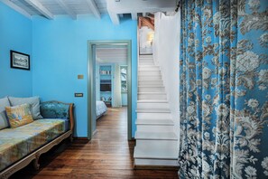 Een slaapkamer met een bed, nachtkastje en een kast. Er is een trap die naar een andere kamer leidt.