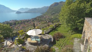 Una vista pintoresca de un pueblo a orillas del lago, con zona de piscina, edificios de piedra y abundante vegetación.